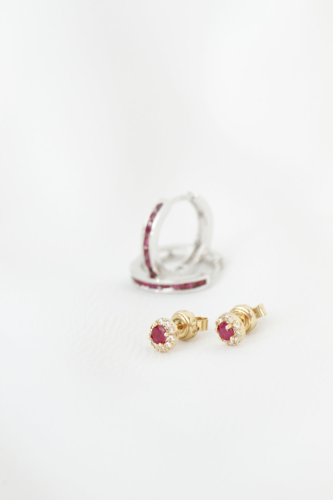 Two pairs of ruby and diamond earrings on white background